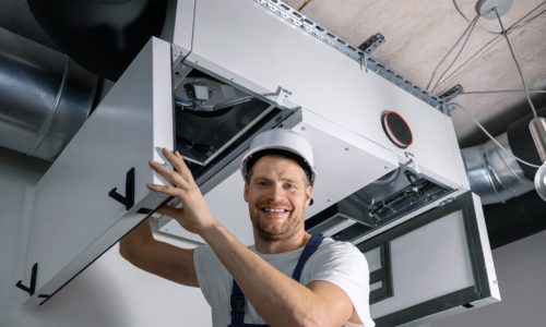 smiling hvac technician at work. ventilation, heating system maintenance and repair